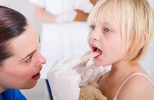 Doctor examining a young girl's throat