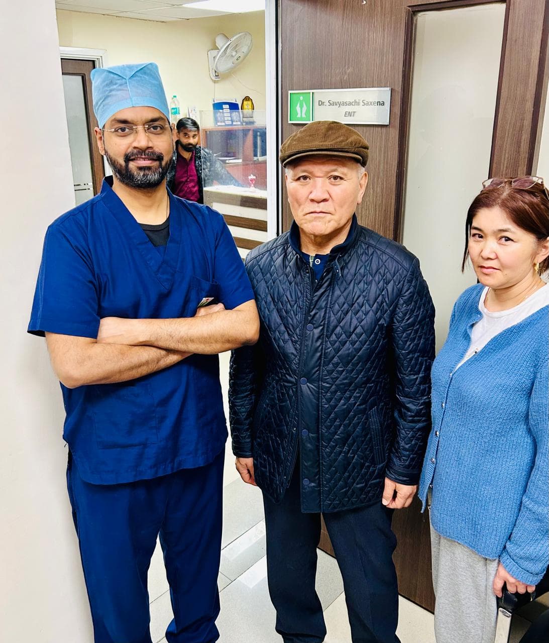 Dr. Savyasachi Saxena in surgical scrubs with patients outside his ENT consultation room